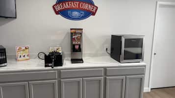 Una zona de cocina con un letrero de Baymont Breakfast Corner, una máquina para gofres, una cafetera y un microondas.