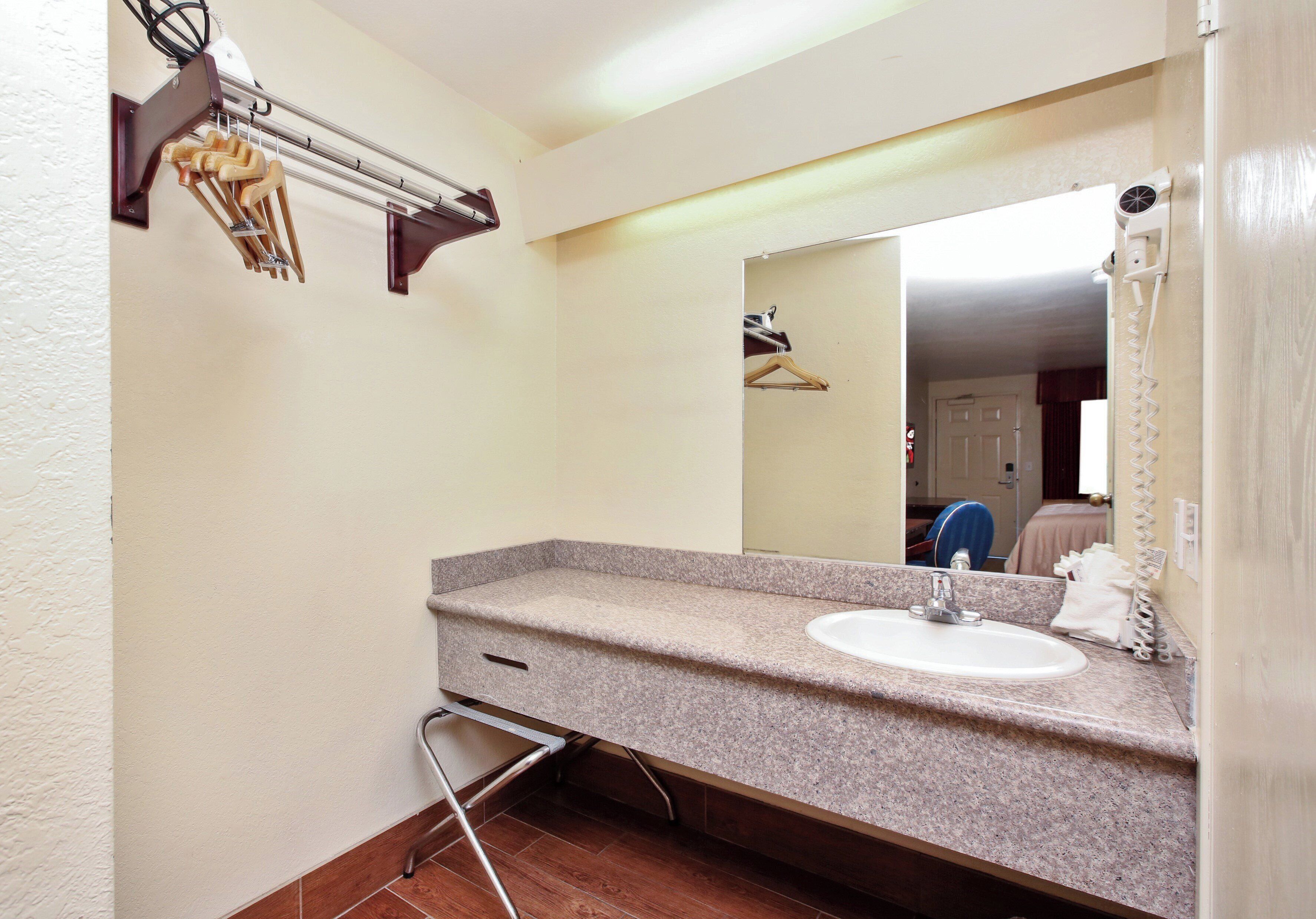 A bathroom with a granite countertop sink, a mirror, a towel rack, and a shower curtain.