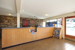 A reception desk with a Red Roof Inn sign, a fire extinguisher, and a window with blinds.