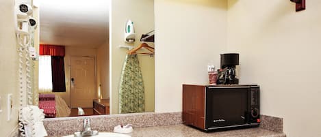 Un baño con lavamanos, espejo y microondas en la encimera.