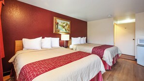 Ein Hotelzimmer mit zwei Betten, einem Bild an der Wand und einer Tür rechts.