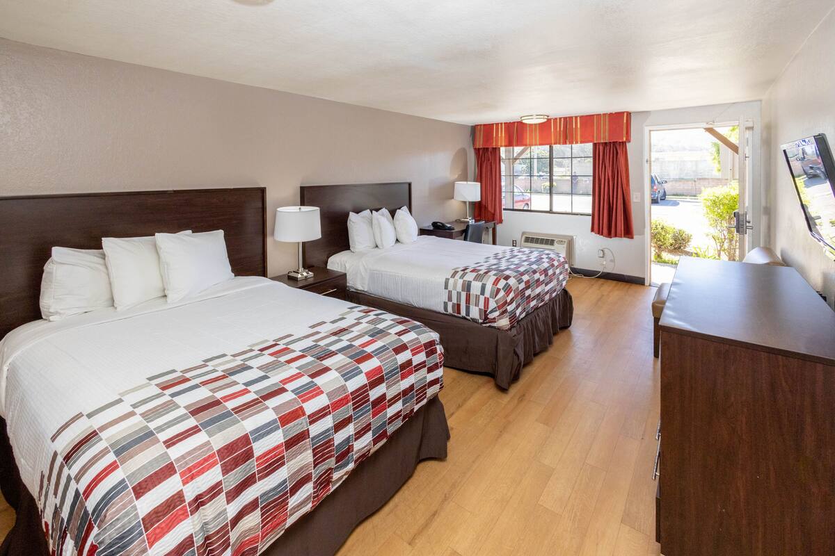 Ett hotellrum med två sängar, ett skrivbord och en TV.