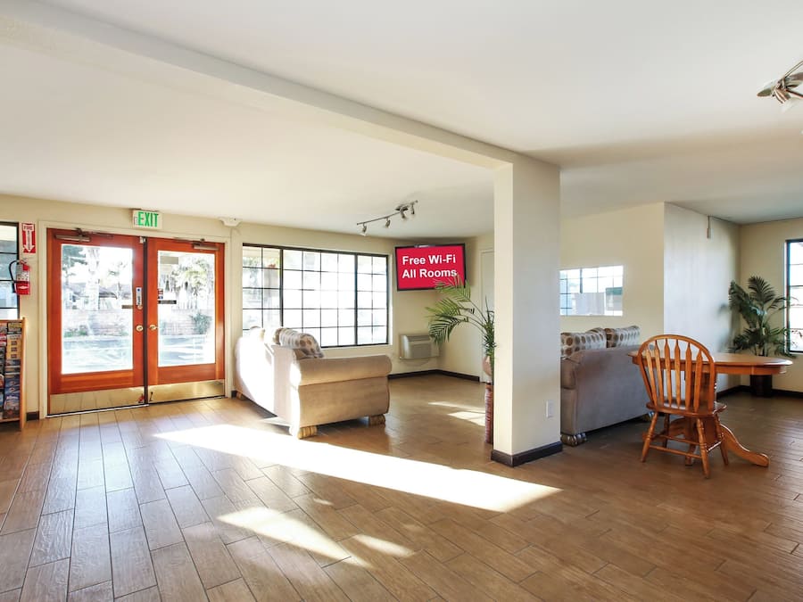 A spacious lobby with a fire extinguisher, exit sign, and a sign indicating free Wi-Fi in all rooms.