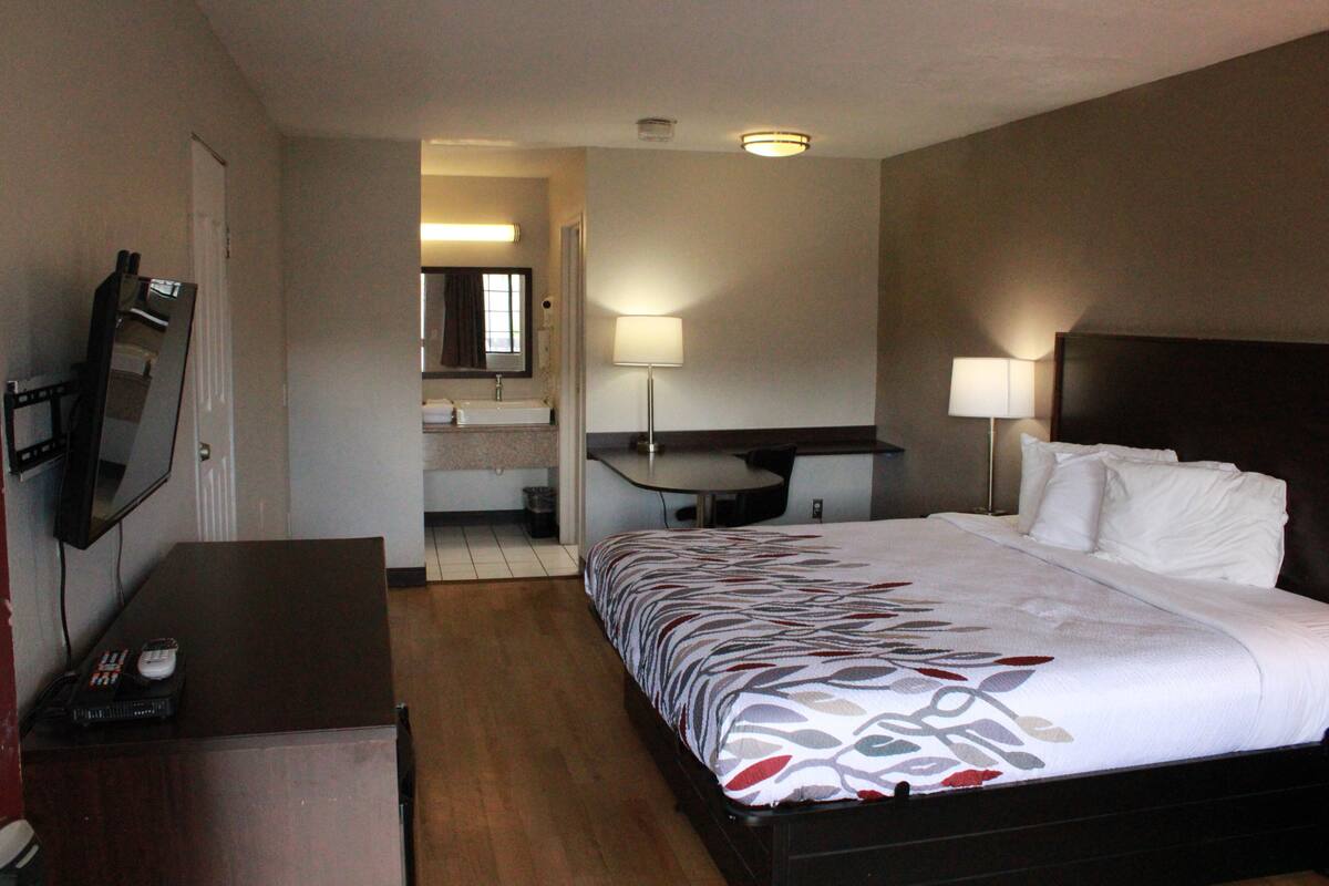 Ett hotellrum med en säng, ett skrivbord, en tv och ett badrum.