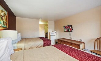 Habitación de hotel con dos camas, un aparador, un microondas y un televisor.