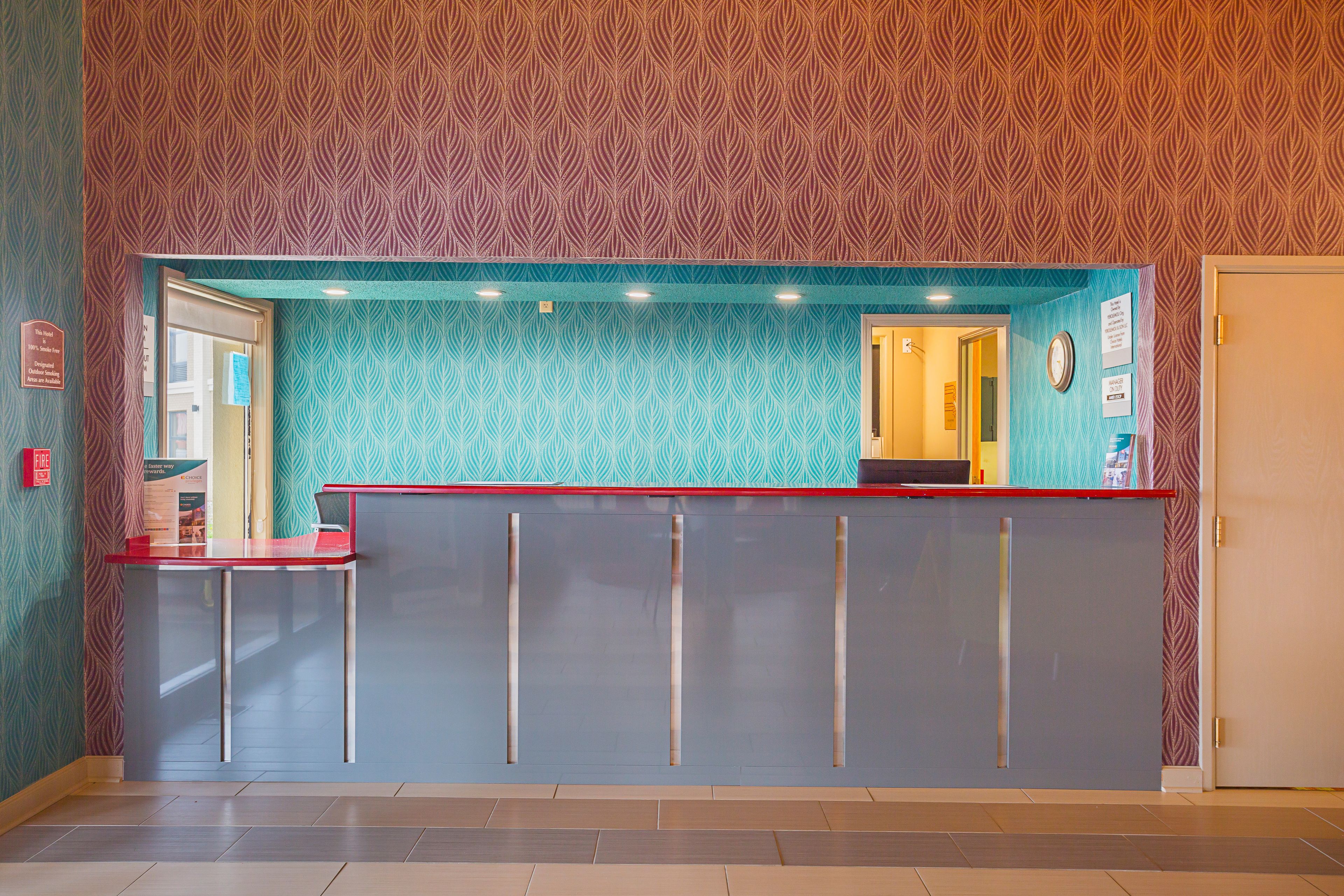 A reception desk with a red top and grey lower section, set against a patterned wall.