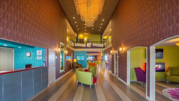A hotel lobby with a reception desk, colorful seating area, and a chandelier.