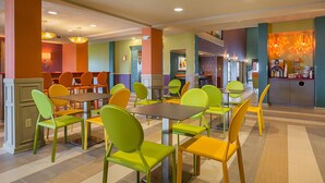 A dining area with multiple tables and chairs, a coffee station, and a view of the kitchen area.