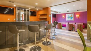 A bar area with stools, a counter, and a seating area with patterned cushions.