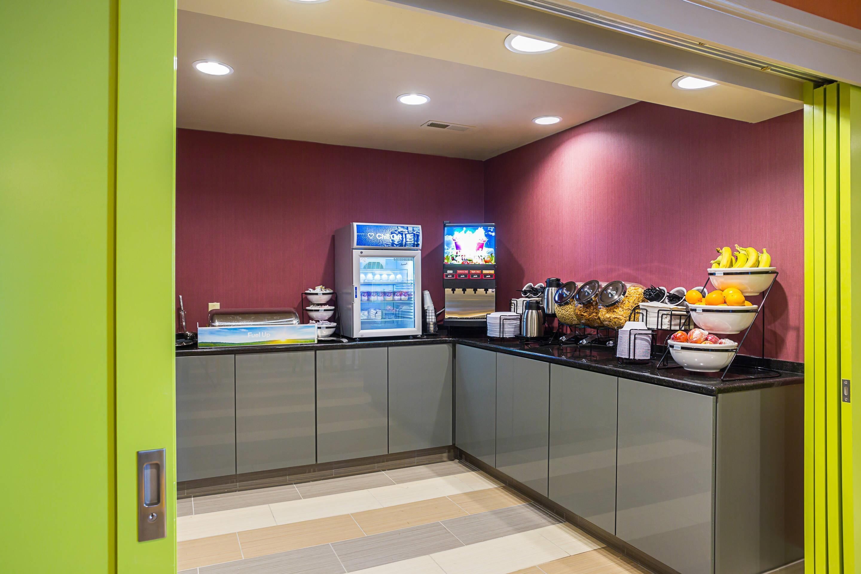 A modern kitchen with a vending machine, a television, and a fruit bowl.