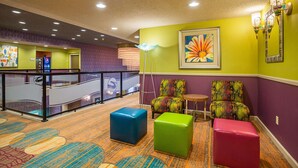 A lobby with colorful carpet, a staircase, and two colorful armchairs.