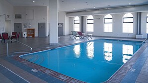 Una piscina interna con acqua cristallina, circondata da lettini e un piccolo angolo relax.
