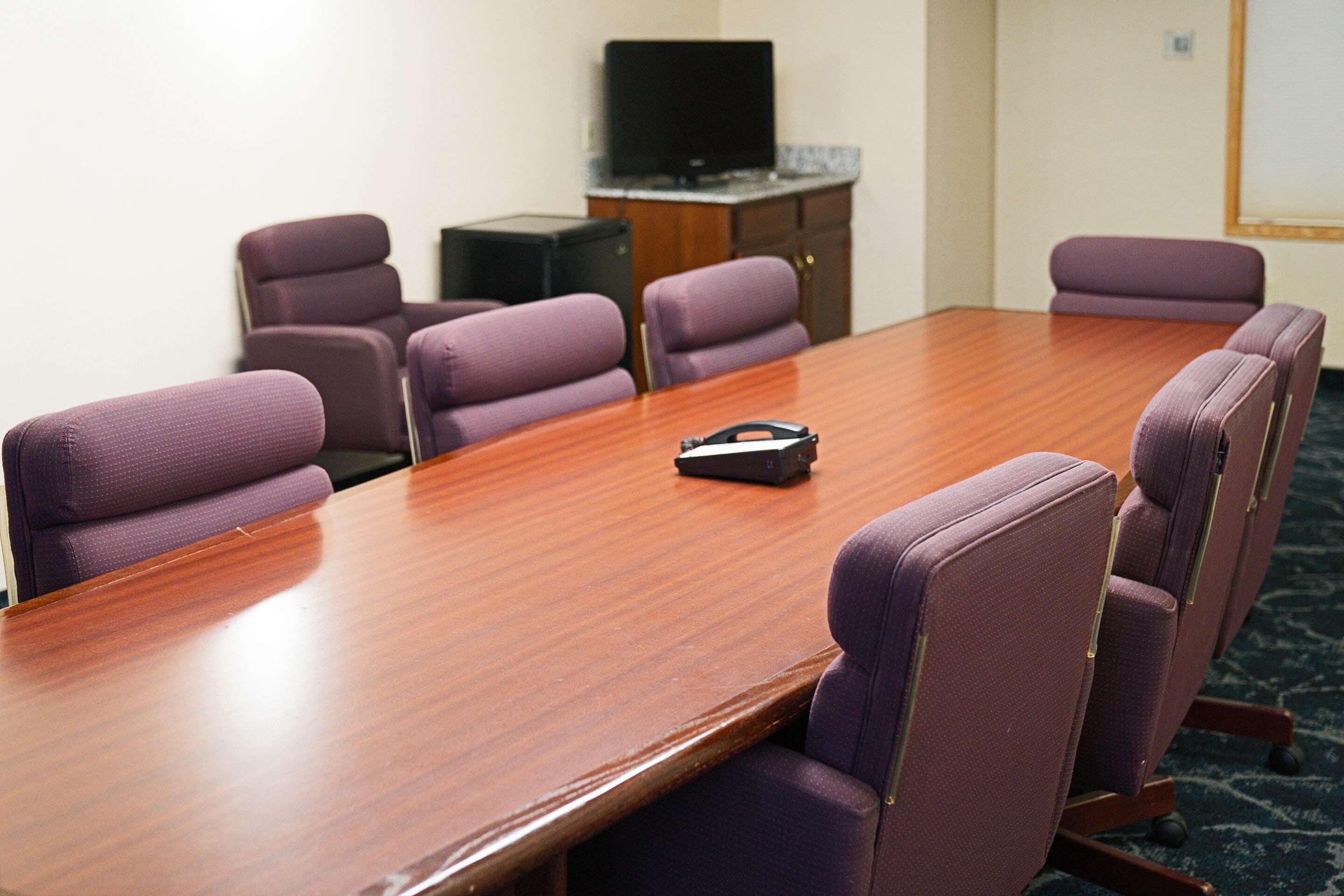 A conference room with a wooden table and purple upholstered chairs.