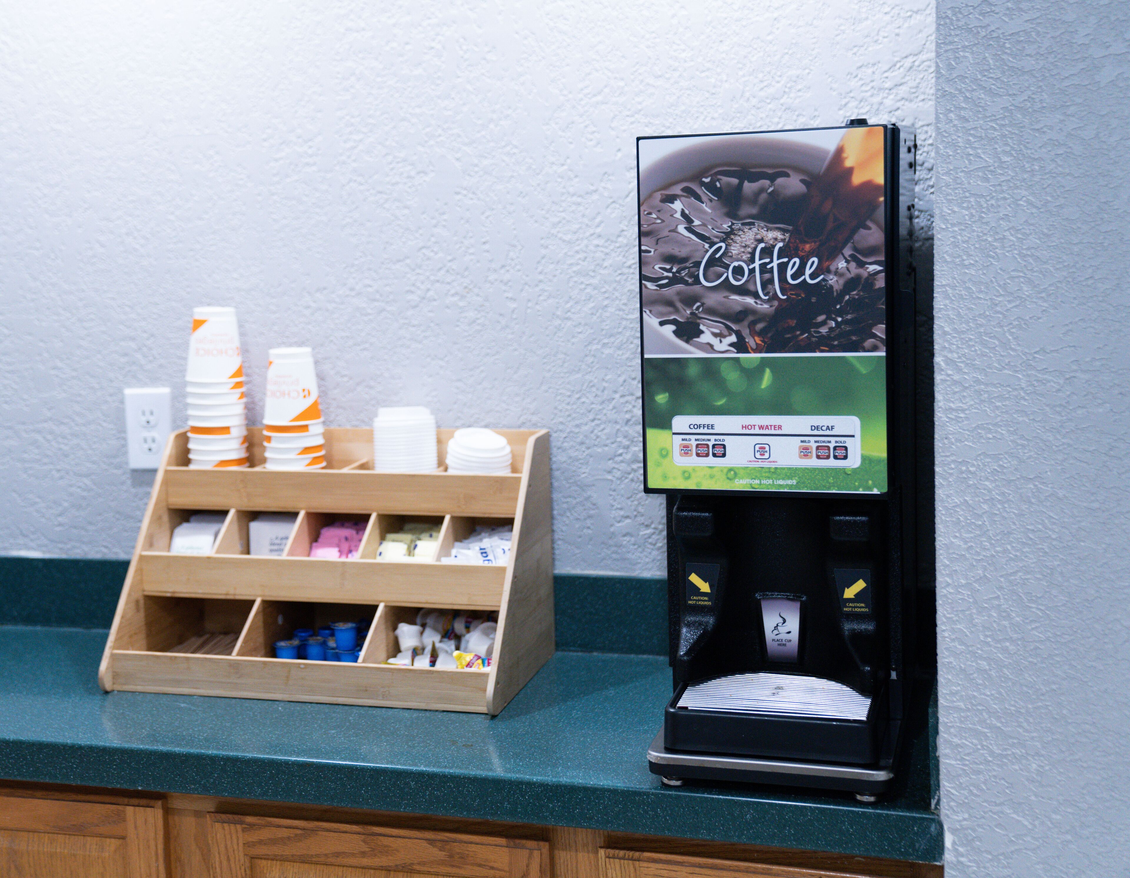 A coffee machine and a dispenser with cups and napkins.