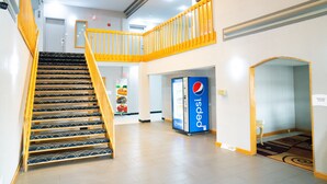 Un'ampia area interna con una scala, una macchina distributrice e la segnaletica del business center.
