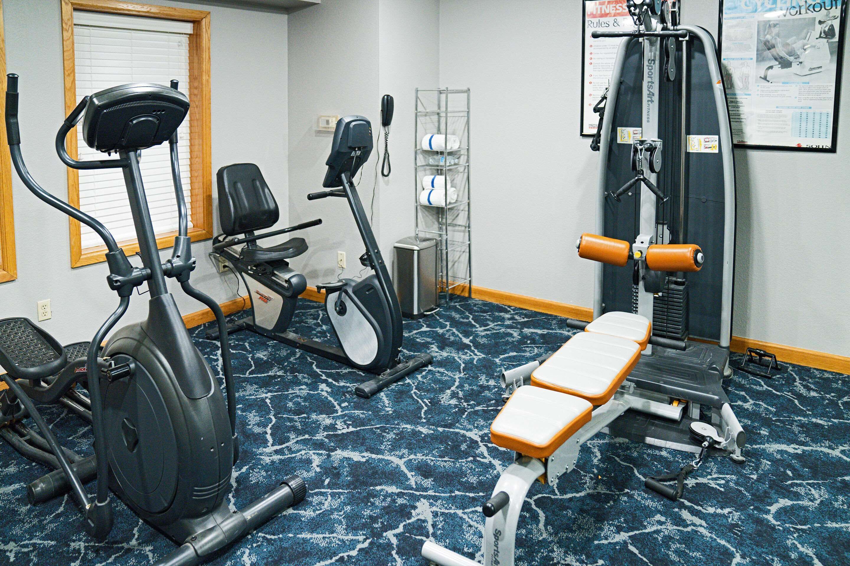 A gym with exercise equipment including an elliptical, a stationary bike, and a bench press.