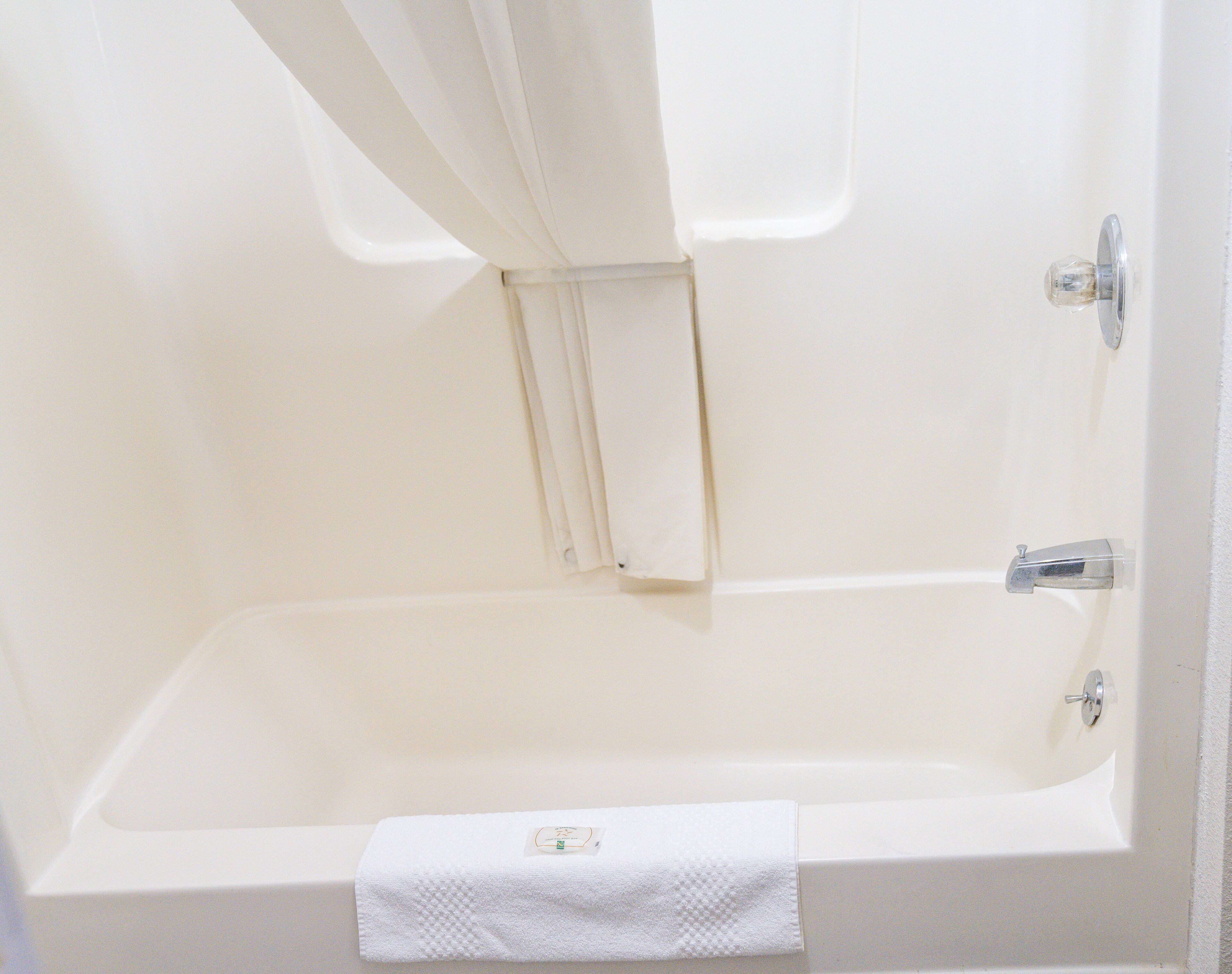 A white bathtub with a towel and a shower curtain.