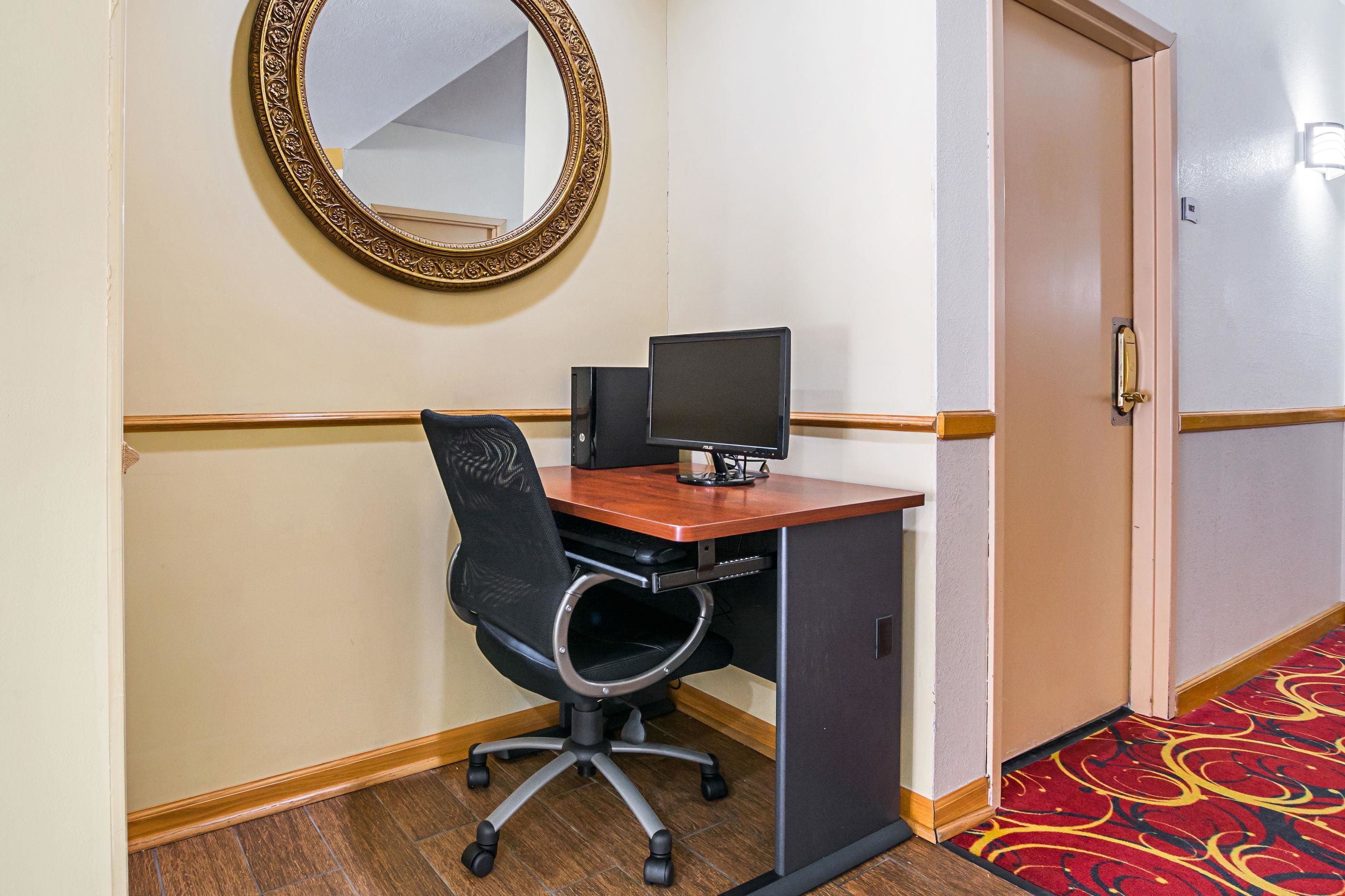 Habitación de hotel con escritorio, computadora y silla.