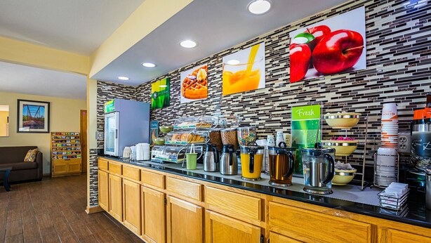 A breakfast bar with a variety of food items, a coffee machine, and a fruit display. - Quality Inn & Suites Greensburg I-74 (Greensburg)