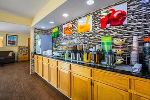 A breakfast bar with a variety of food items, a coffee machine, and a fruit display.
