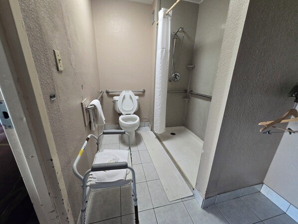 Un baño con inodoro, ducha y un asiento accesible para sillas de ruedas.
