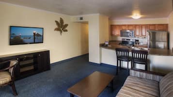 A compact living space with a TV, seating area, and kitchenette.