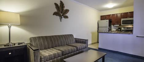 Ein gemütlicher Wohnbereich mit Sofa, kleinem Tisch, Lampe und Küchenzeile.