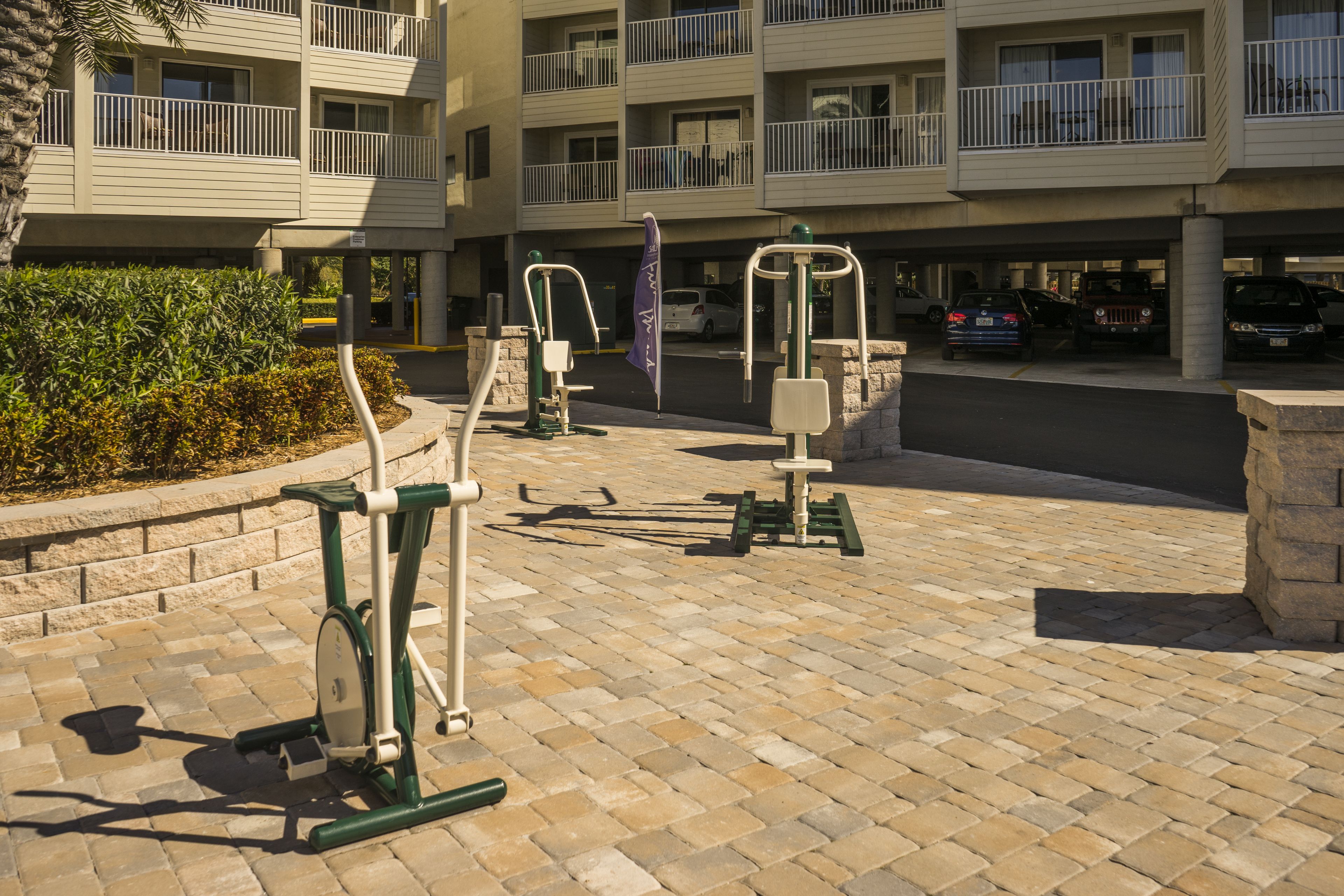 Outdoor exercise equipment in a courtyard with a multi-story building in the background.