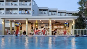 Un hotel con zona de piscina, mobiliario exterior y restaurante frente a la playa.