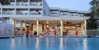 A hotel room with a balcony, a dining area, and a sofa. at Sailport Waterfront Suites