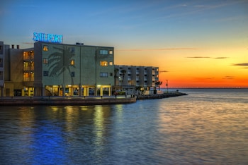 A beachfront view with a clear sky, palm trees, and a water body. at Sailport Waterfront Suites