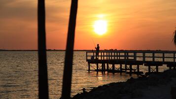 A pier extending into calm water during sunset.