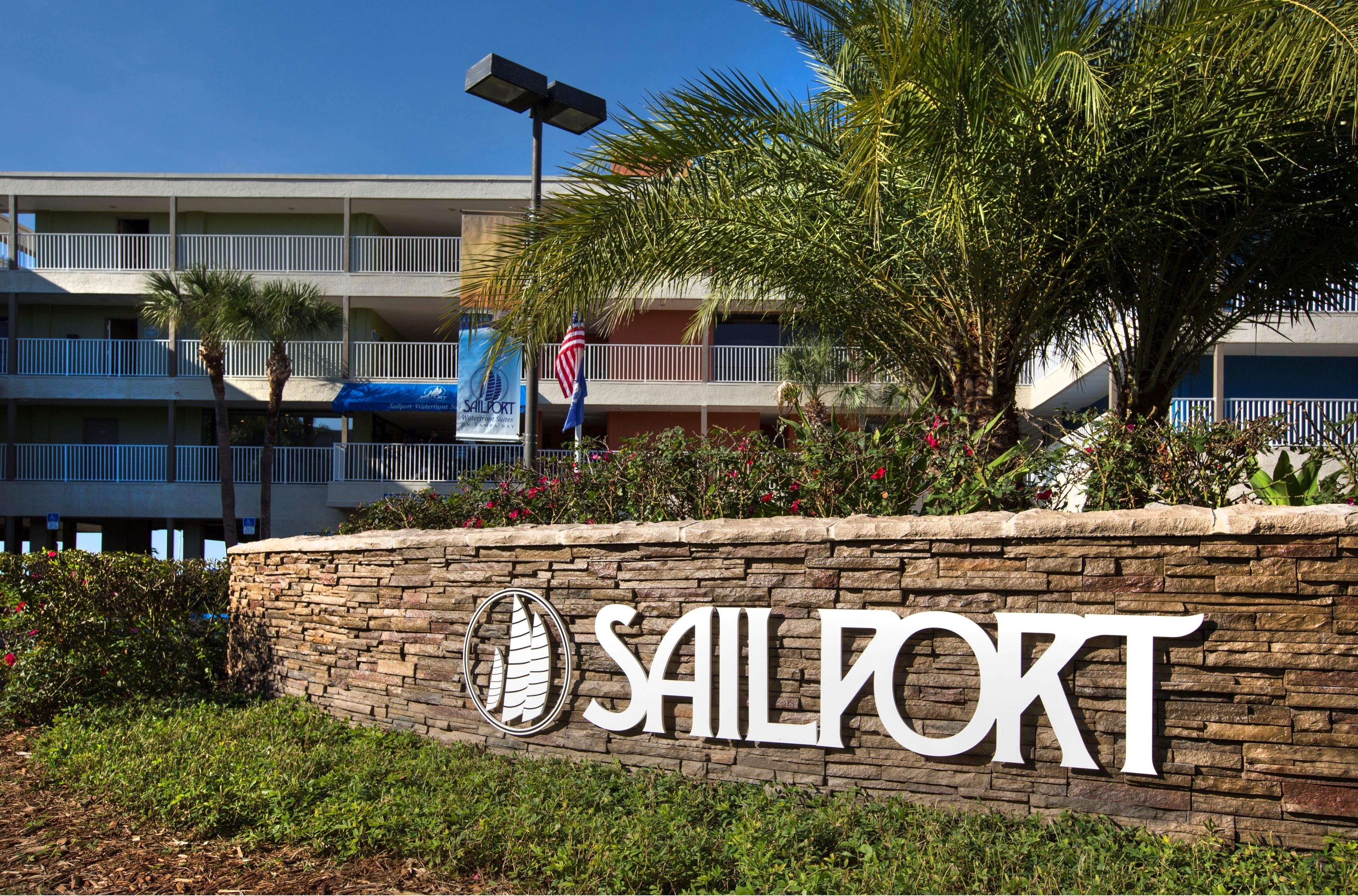 Eine Steinmauer mit der Aufschrift "Sailport" und einer Palme.