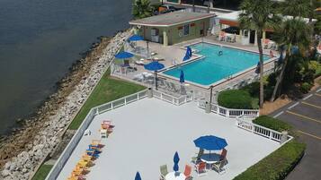 A hotel with a pool area, outdoor seating, and a view of the water.