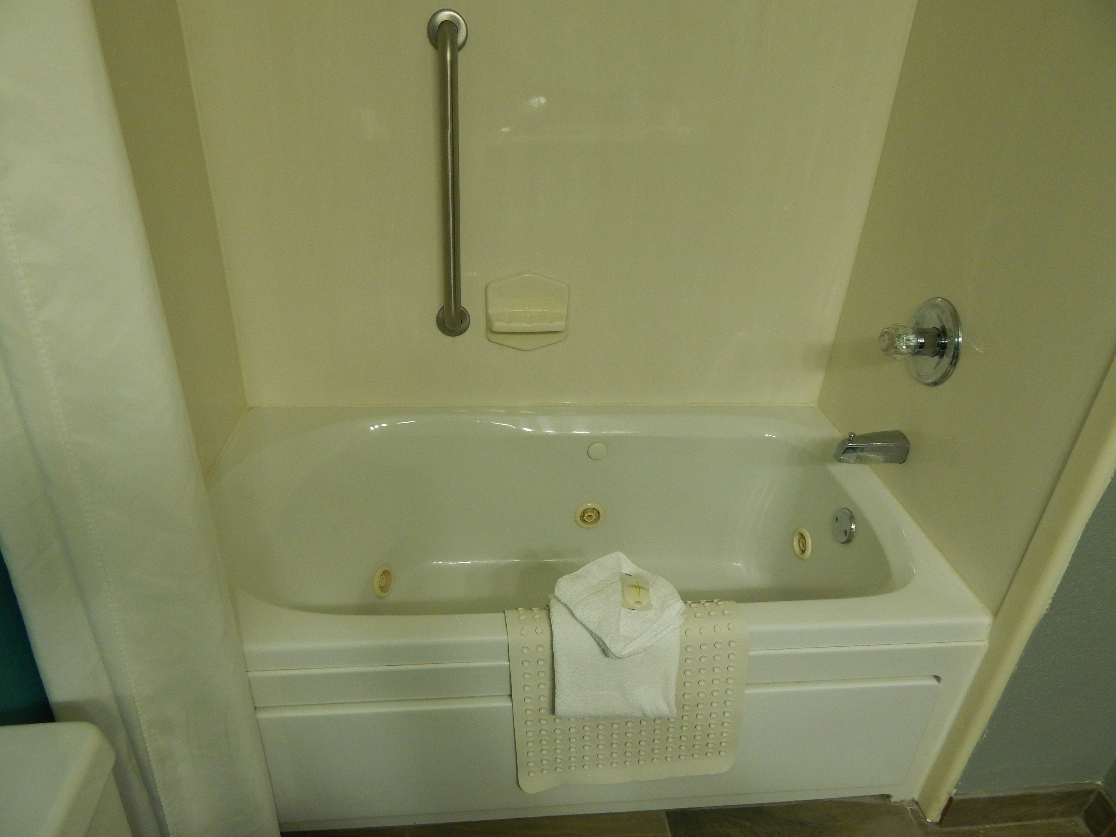 Une salle de bain équipée d’une baignoire, d’une barre d’appui, d’un porte-savon et d’un porte-serviettes.