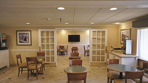 A hotel lobby with multiple seating areas, a television mounted on the wall, and a window providing natural light. - La Quinta Inn & Suites by Wyndham Tampa Fairgrounds - Casino (Tampa)