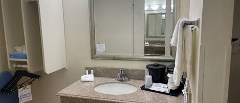 A bathroom with a sink, mirror, towel rack, and a sign for Wyndham Rewards.