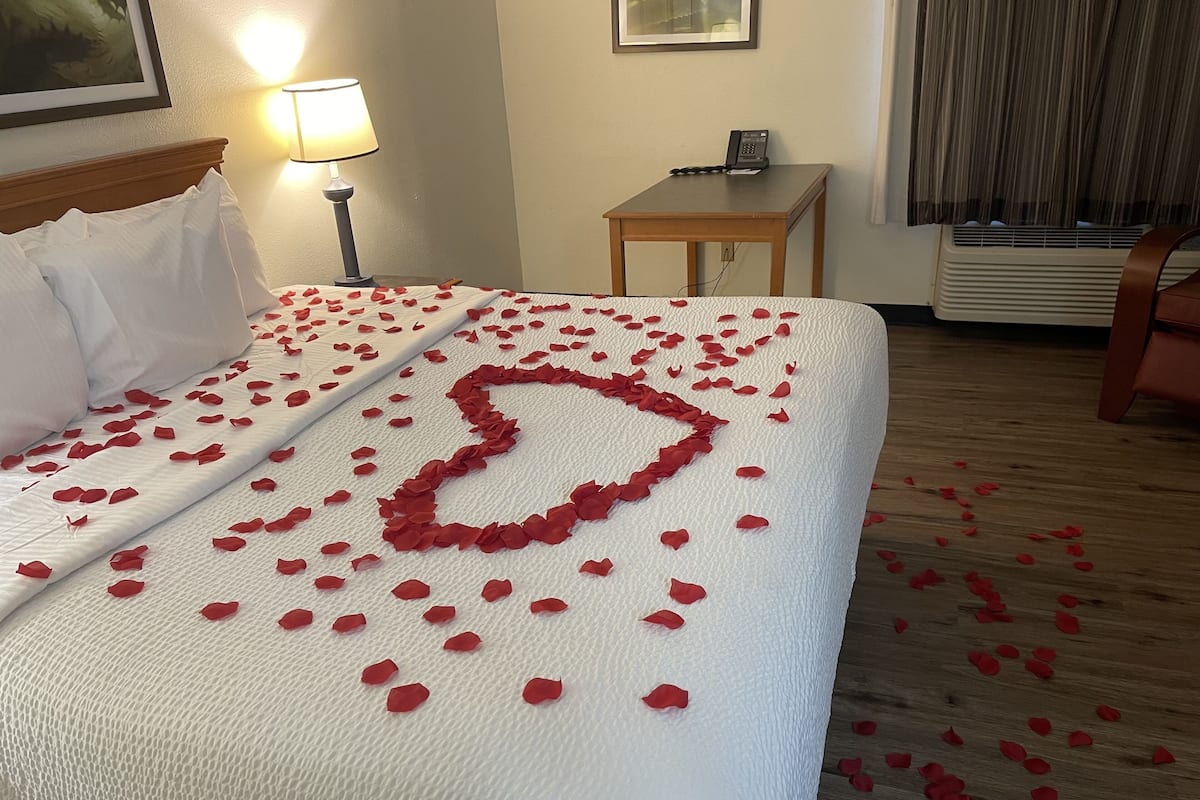 A hotel room with a neatly made bed, a bedside lamp, a telephone, and a small table.