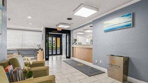 Un vestíbulo de hotel con mostrador de recepción, zona de estar y un amplio ventanal.