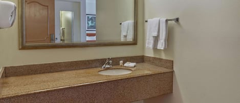 Baño con lavamanos de encimera de granito, un espejo y un perchero para toallas.