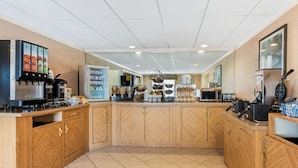 Una cocina con muebles de madera, cafetera, microondas y refrigerador.