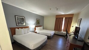 Una habitación de hotel con dos camas, un escritorio, un televisor y una ventana con cortinas.