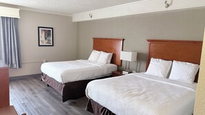 A hotel room with two beds, a desk, and a chair.