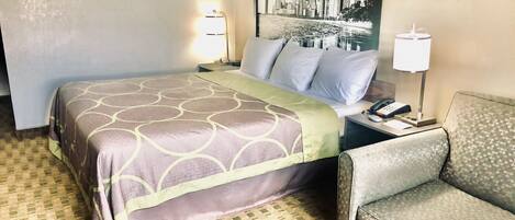 Habitación de hotel con cama, una silla, una mesita de noche y una lámpara.
