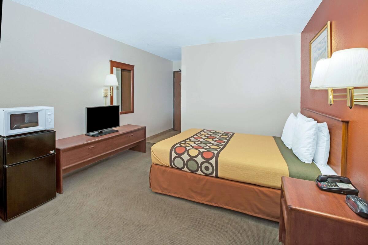 Habitació d'hotel amb llit, televisió, microones, escriptori i telèfon.
