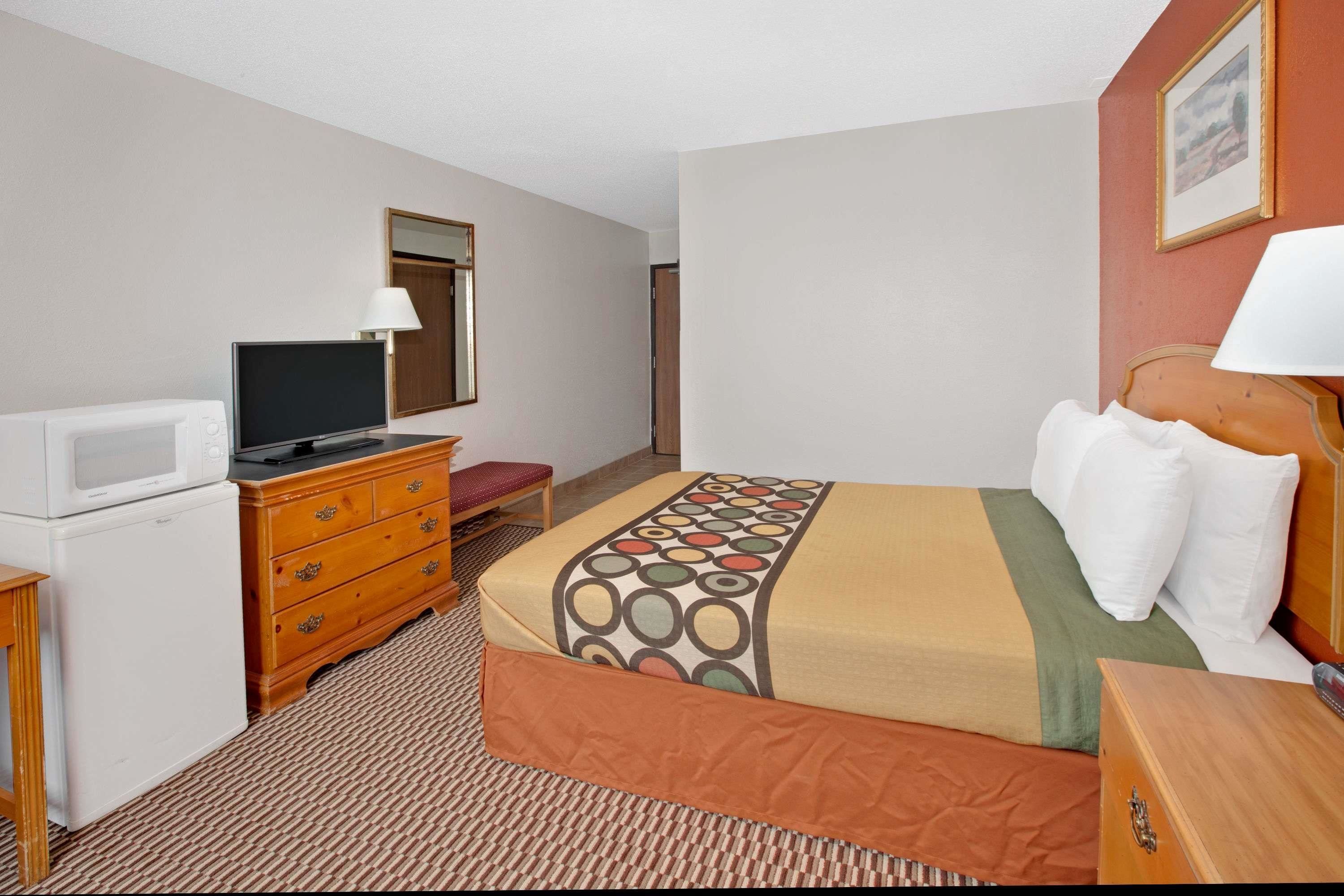 A hotel room with a bed, a television, a dresser, and a microwave.