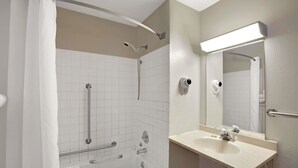 Un baño con bañera, lavamanos, espejo y ducha con cabezal de ducha manual.