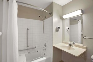 Bathroom features a bathtub, sink, and mirror, with a towel rack and light fixture.