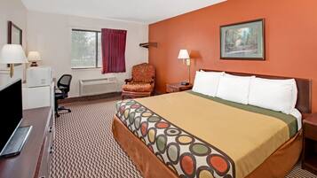 A hotel room with a large bed, a desk with a computer, a chair, a window with curtains, and a painting on the wall.