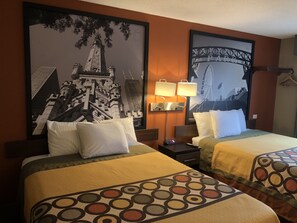 A hotel room with two beds, each with a patterned bedspread, a nightstand with a lamp, and a large framed picture of a bridge on the wall. - Super 8 by Wyndham Crystal Lake (Crystal Lake)